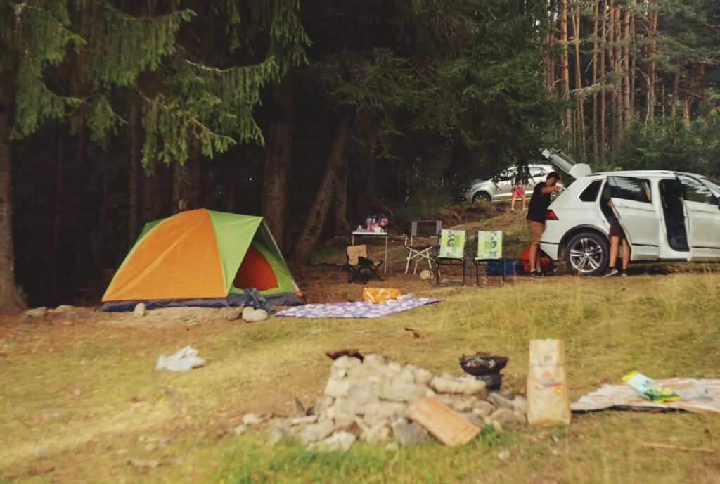 Peaceful camping scene in the forest with tent, car, and campfire setup
